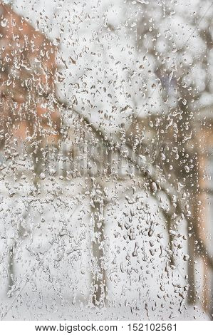 Texture of the ice and drops on the window glass in inclement winter weather close up