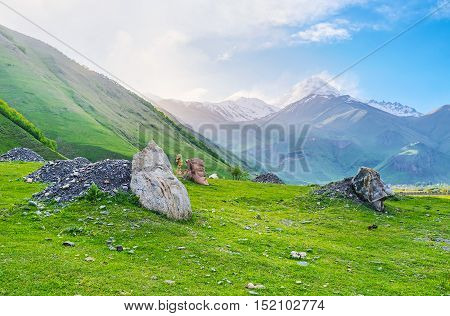 The meadow at the mountain foot in Sno village is occupied with the boulders with carved faces of most famous Georgian cultural figures Kazbegi Georgia.