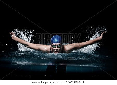 Profesional woman swimmer swim using breaststroke technique on the dark background