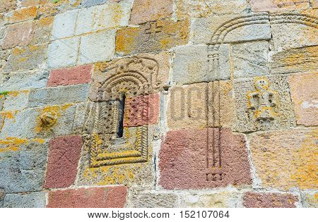 The wall of Tsminda Sameba (Holy Trinity) Church with the old preserved carved ornamentations and depiction of the ancient dinosaurs above the window Gergeti Georgia.