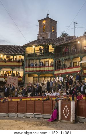 Chinchon Spain - October 15 2016: Plaza square Mayor of Chinchon adapted as a bullring Detail of balconies illuminated dressed with the Spanish flag beautiful sunset at Chinchon Spain