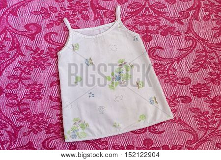 Light Sundress with green and blue little flowers thin spaghetti straps for newborns .Things for babies on a pink blanket. Clothes for baby close up.