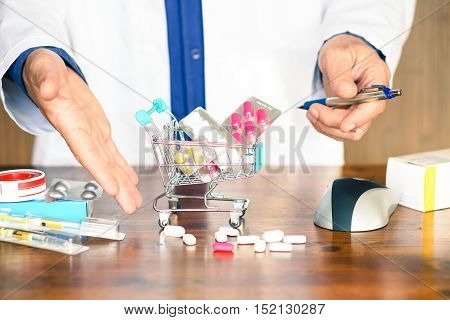 Pills and medicinal products inside shopping trolley - Doctor hands showing tablets and pharmaceutical package on wooden table - Concept of online medicines purchase risk