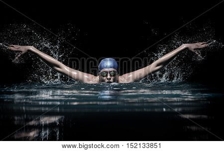 Profesional woman swimmer swim using breaststroke technique on the dark background