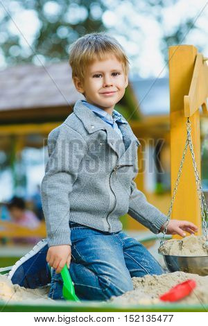 happy little boy playing in sandbox at playground.