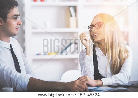 Attractive caucasuan man and woman discussing something at workplace. Teamwork and partnership concept