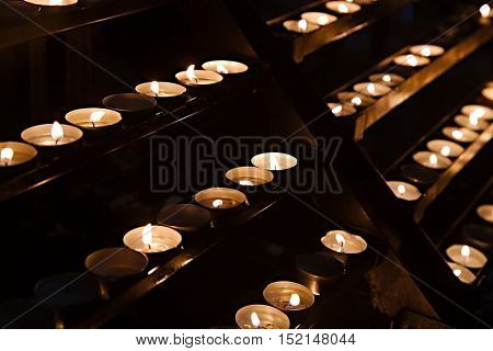 Rows of burning candles in a dim church