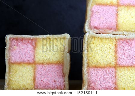Freshly Cut Battenberg Cake Slices On Wooden Board With Dark Background. Pink And Yellow Sponge Cove