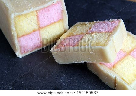 Freshly Cut Battenberg Cake On Dark Slate Board. Pink And Yellow Sponge Covered In Marzipan