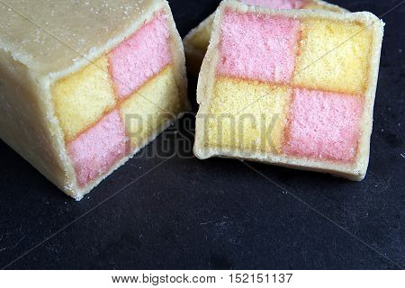 Freshly Cut Battenberg Cake On Dark Slate Board. Pink And Yellow Sponge Covered In Marzipan