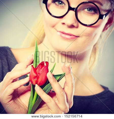 Delicacy and subtlety of women. Young adorable woman with spring flower. Portrait of beauty delicate girl in glasses with red beautiful tulip.