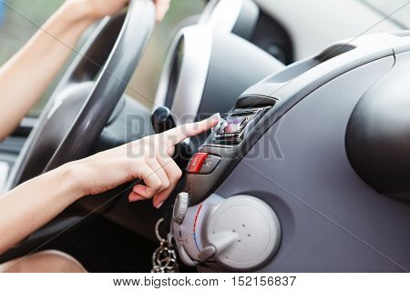 Distracted driver. Attractive blonde woman changing radio station in her car