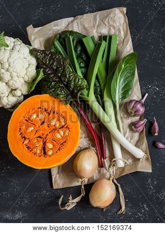 Fall harvest - pumpkin cauliflower chard leeks broccoli onion garlic. Autumn vegetables. On a dark background top view