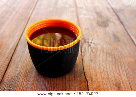A cup with a hot drink on a wooden table outdoors
