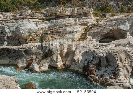 At the foot of the hill on which La Roque sur Cèze in France lies swirl spectacular waterfalls and rapids of the Cascades du Sautadet.