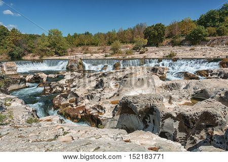 At the foot of the hill on which La Roque sur Cèze in France lies swirl spectacular waterfalls and rapids of the Cascades du Sautadet.