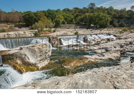 At the foot of the hill on which La Roque sur Cèze in France lies swirl spectacular waterfalls and rapids of the Cascades du Sautadet.