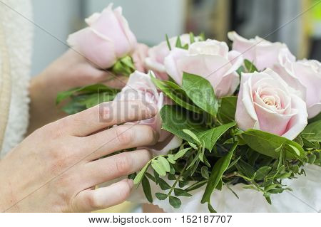 background florist girl collects bouquet of pink roses in a hatbox in the floristic salon