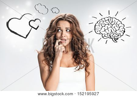 The young woman's portrait with frightened emotions on gray background. concept of choice between the senses and the mind