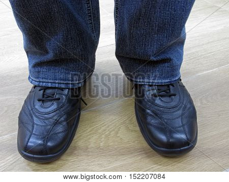 Man stands in jeans and in casual shoes. Man in jeans and everyday shoes. Man in jeans and casual shoes. Male legs in jeans and boots.