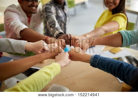 education, school, teamwork and people concept - close up of international students hands making fist bump gesture