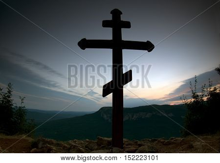 cross on the top of a mountain at sunset