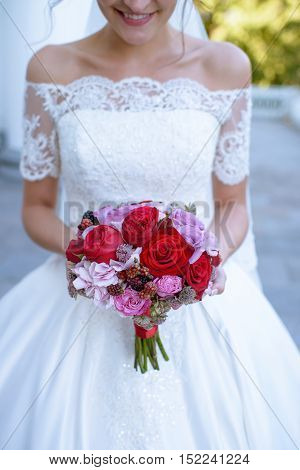 Beautiful bride is holding a wedding colorful bouquet. Beauty of colored flowers. Close-up bunch of florets. Bridal accessories. Female decoration for girl. Details for marriage and for married couple
