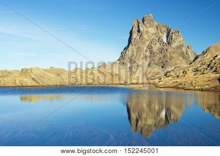 Midi Dossau Peak reflected in a lake. Ossau Valley, Pyrenees National Park, Pyrenees, France.
