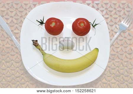Tomatoes mushroom and banana arranged in a happy face on a plate