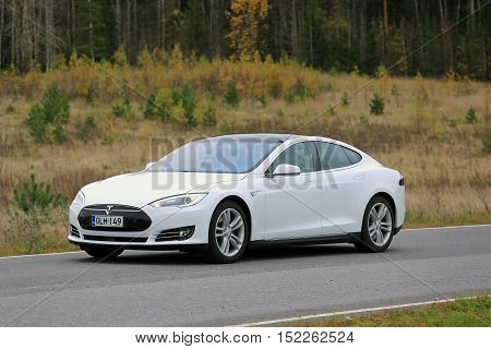 PAIMIO, FINLAND - OCTOBER 16, 2016: White Tesla Model S electric car travels along road through autumn scenery in South of Finland.