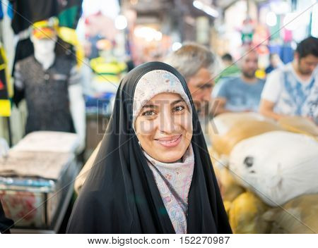 Beautiful Muslim woman spending time on traditional Iranian bazaar market street between people for shopping
