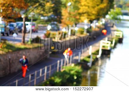 Abstract high key blurred image of street workers on the river side in fall. Unrecognizable faces.