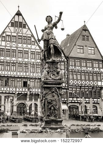 Frankfurt am Main, Germany - May 29, 2016: Old town square Romerberg with Justitia statue in Frankfurt Germany. Black and white photography sepia toned.