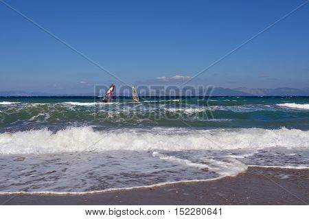 Beautiful view on the Aegean sea with two windsurfers from sandy beach in Artemis Greece