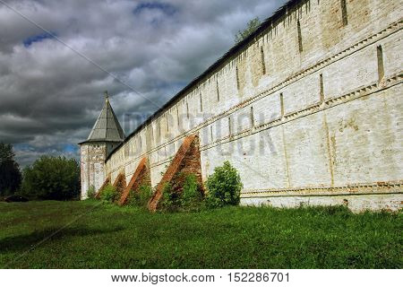 high white stone wall of the ancient Orthodox monastery with brick buttresses