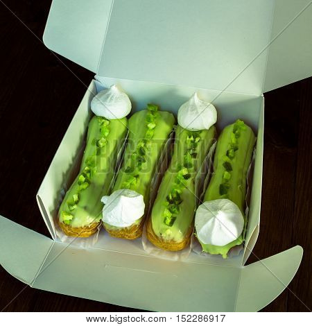 French dessert. Tasty lime eclairs with meringue in the box
