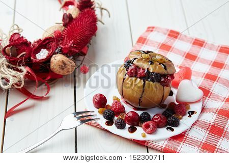Baked apple with berries and chocolate sauce. Wooden background. Healthy lifestyle.Diet and weight loss concept. Low calories dinner. Vitamin B. Healthy food.
