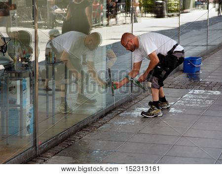 SODERTALJE SWEDEN - July 20 2012: A man cleaning the windows of the shop window to the department store Kringlan in Sodertalje.