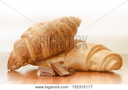 Two baked croissants with chocolate. on a wooden surface. White background