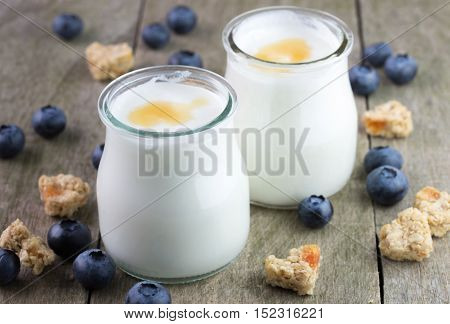 White yougurt in glass bowls on natural wooden table.