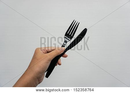 isolates woman hold pair of plasitc spoon and fork with left hand