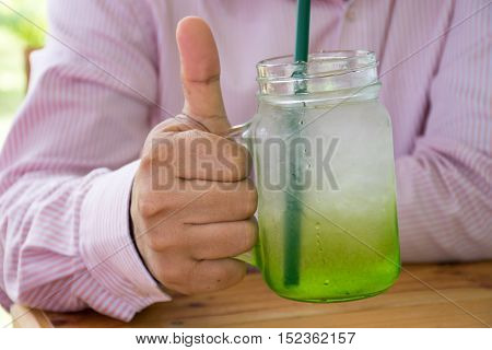 Man holding a mug of juice and show good taste sign