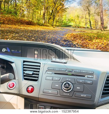 view of modern car dashboard with start power engine button and keys, fall road in background