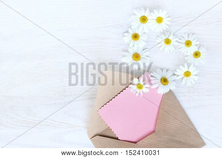flat lay with an open letter to the paper flying off daisies outside view from above / idea messages from your heart