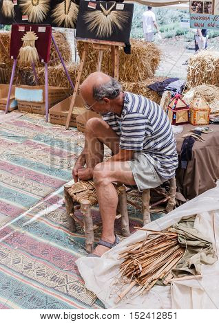 Elderly Man Weaves Chair At The Fair