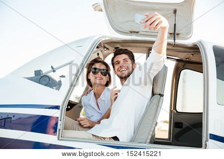 Happy smiling couple making selfie with smartphone inside plane cabin after landing