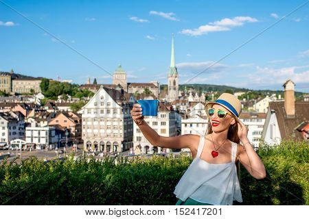 Young female tourist making selfie photo on the beautiful old townscape background in Zurich city. Having a happy vacation in Switzerland