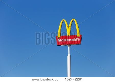 Vasteras, Sweden - July 3, 2015: McDonald's yellow and red logo advertising sign placed on a pole with a clear blue sky