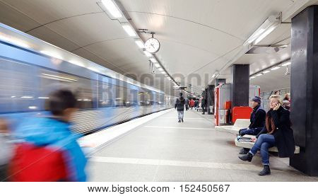 Stockholm, Sweden - April 17, 2014: Upper platform at the metro station T-Centralen in Stockholm Sweden with people waiting and in motion when a subway train with destination Akeshov arrives at the station.