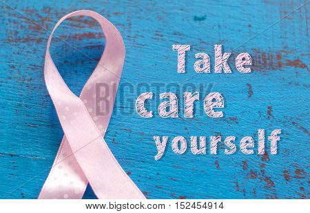 Breast cancer awareness ribbon on the blue wooden background.